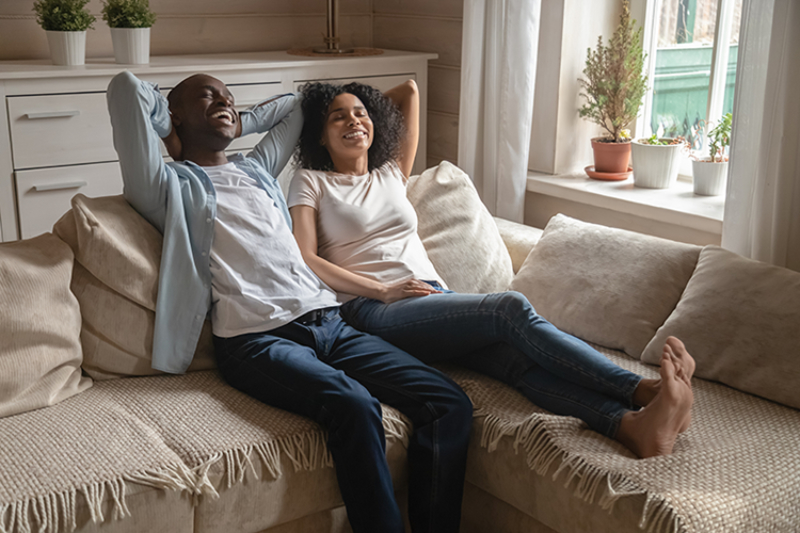 couple sitting on their couch, smiling and looking relaxed.